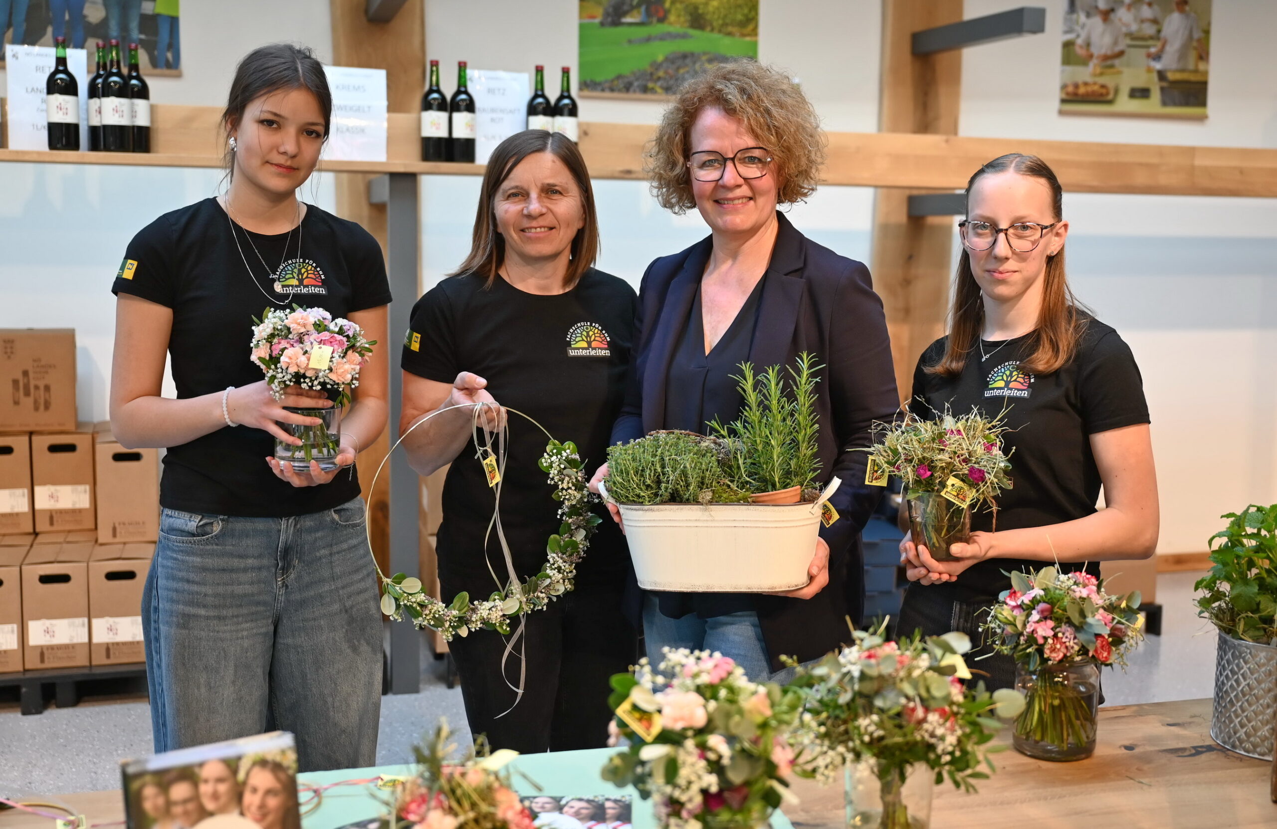 Schülerin Lea Biberosch, Fachlehrerin Barbara Hobiger, Bildungs-Landesrätin Christiane Teschl-Hofmeister und Schülerin Sonja Hoppel präsentieren selbst gestaltete Türkränze und Kräutertöpfe